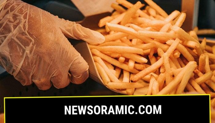 A person scoops French fries at a shop. — Unsplash