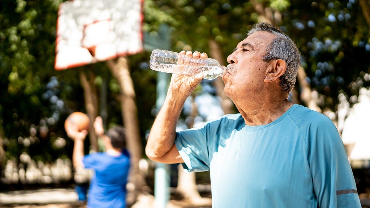 Senior man drinking water at the basketball court