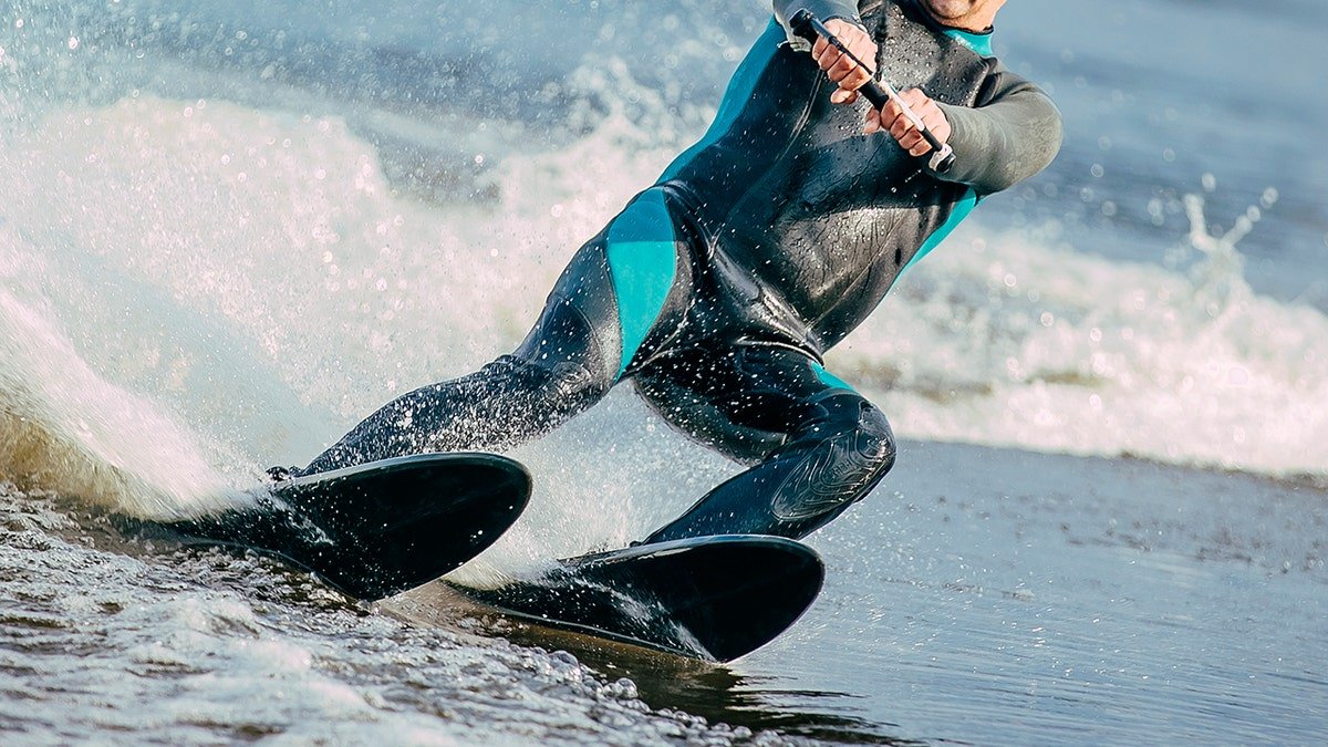 Body of a man seen riding water skis on lake in summer.