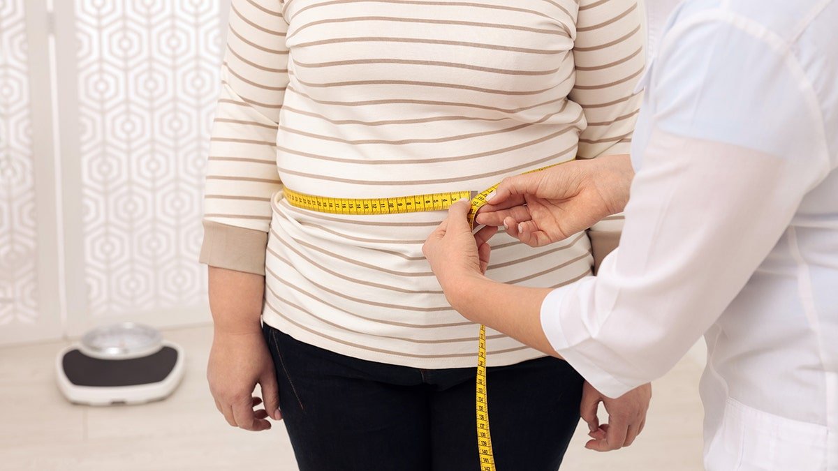 doctor measures woman's waist
