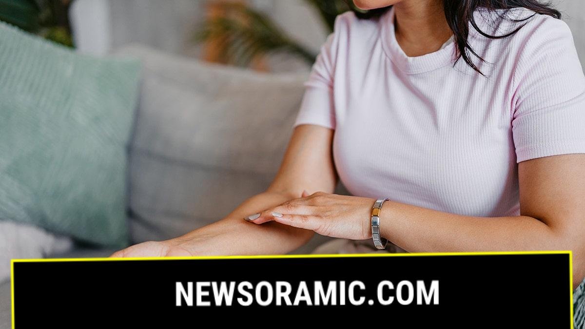 woman examines skin on arm