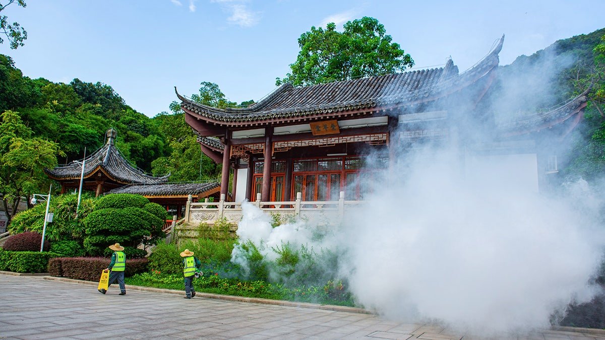 Spraying for mosquitoes in front of a temple