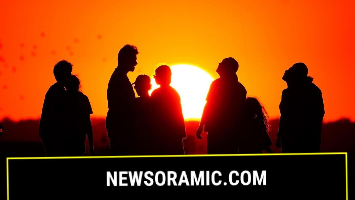 A group of people silhouetted against a background of an orange sky and a setting Sun