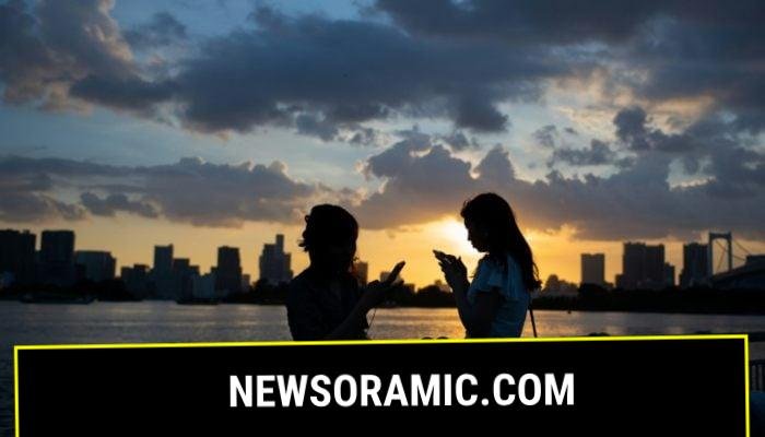 Two women using their smartphones in Japan. — AFP