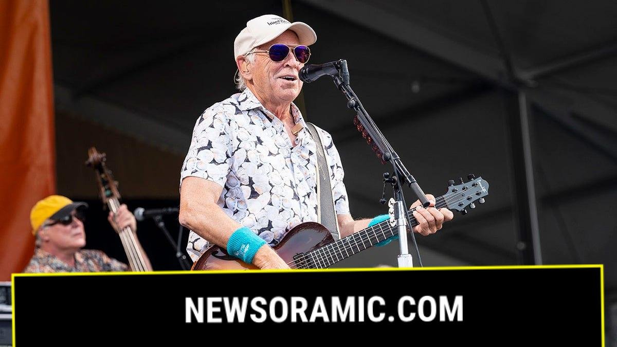 Jimmy Buffett holds guitar on stage