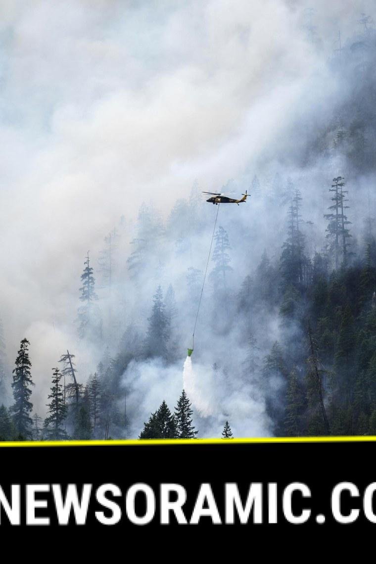 A helicopter drops water on a hotspot on the fire's edge on Aug. 6, 2025.