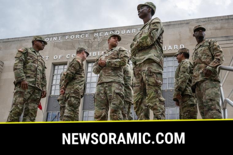 Members of the National Guard stand outside on steps in front of a building