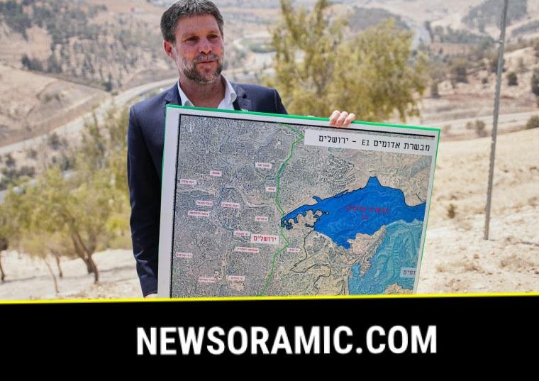 Bezalel Smotrich stand outside and holds a map that shows the E1 settlement