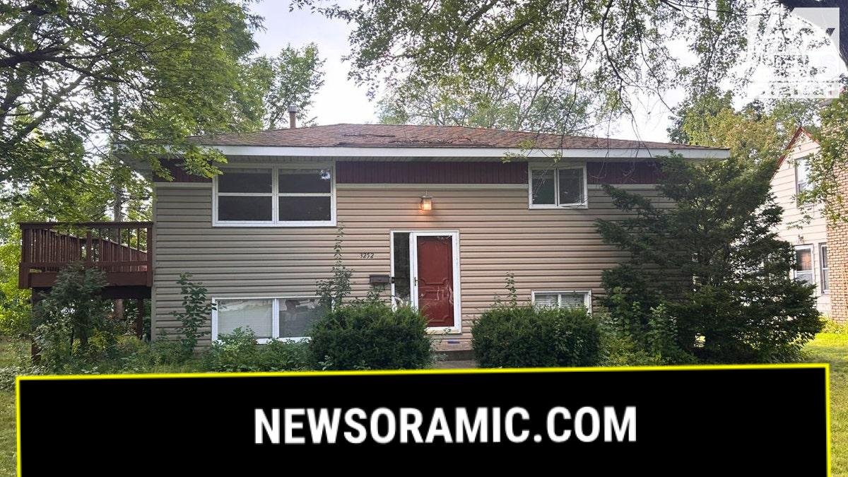 Front exterior of a beige split-level house in St. Louis Park with red front door and small lawn, linked to Robin Westman.