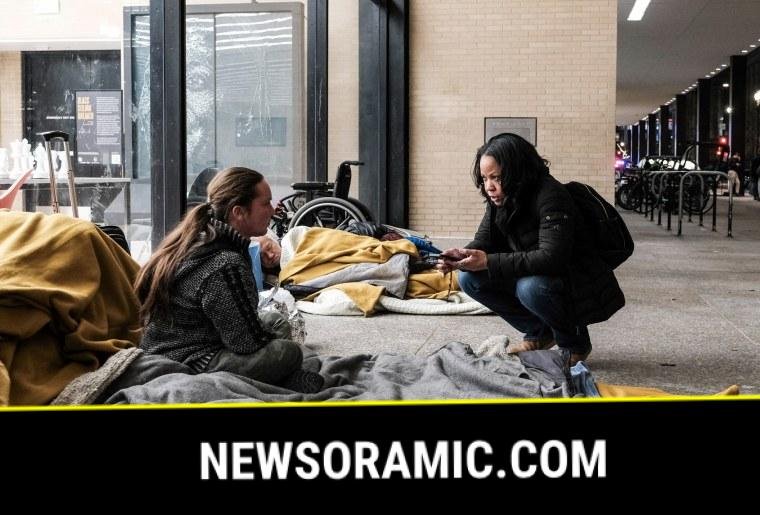 Rachel Pierre, right, speaks with a homeless woman sitting on a blanket outside