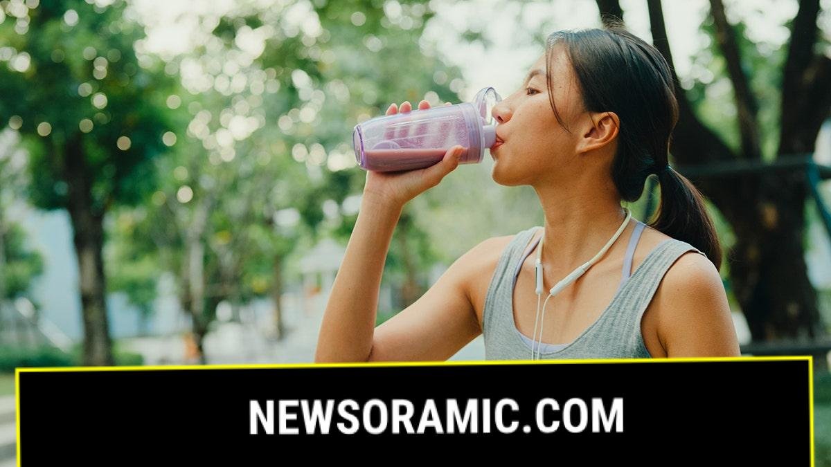 A young woman drinking a brightly colored protein shake after a workout