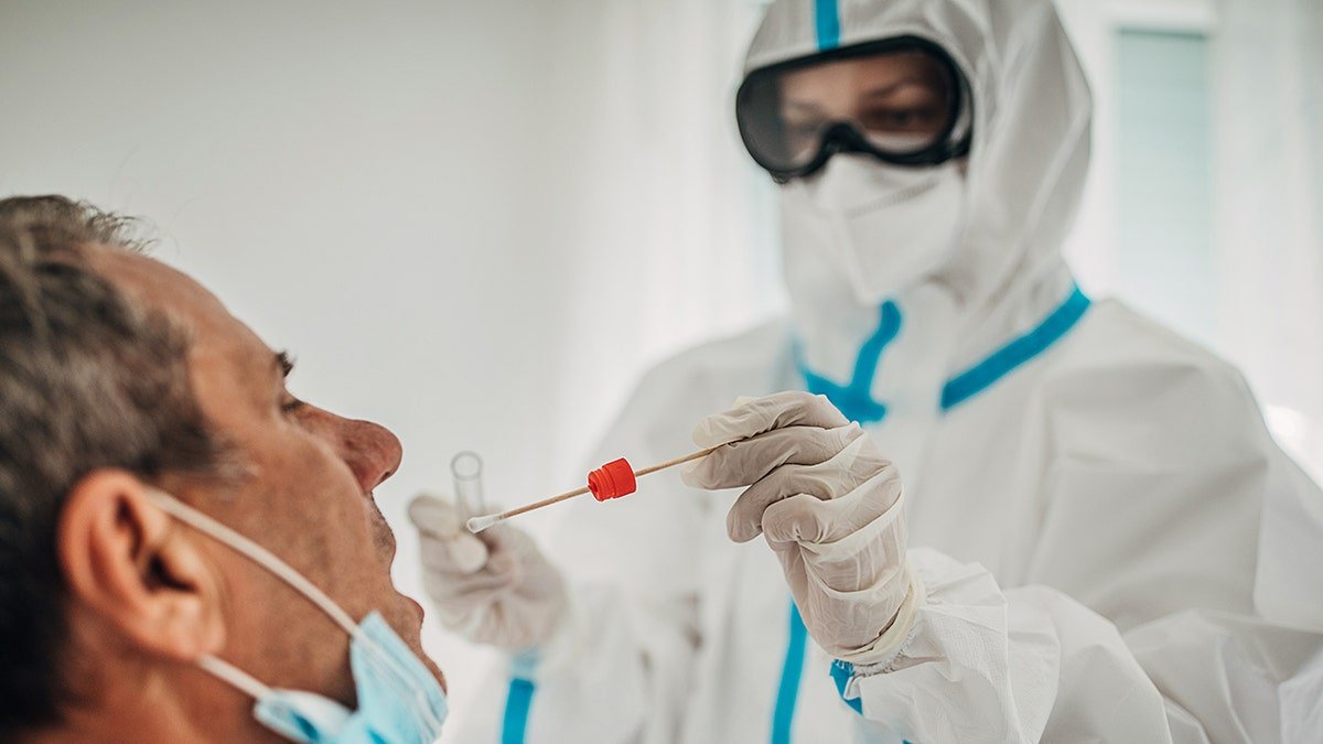 doctor in protective gear swabs infected patient