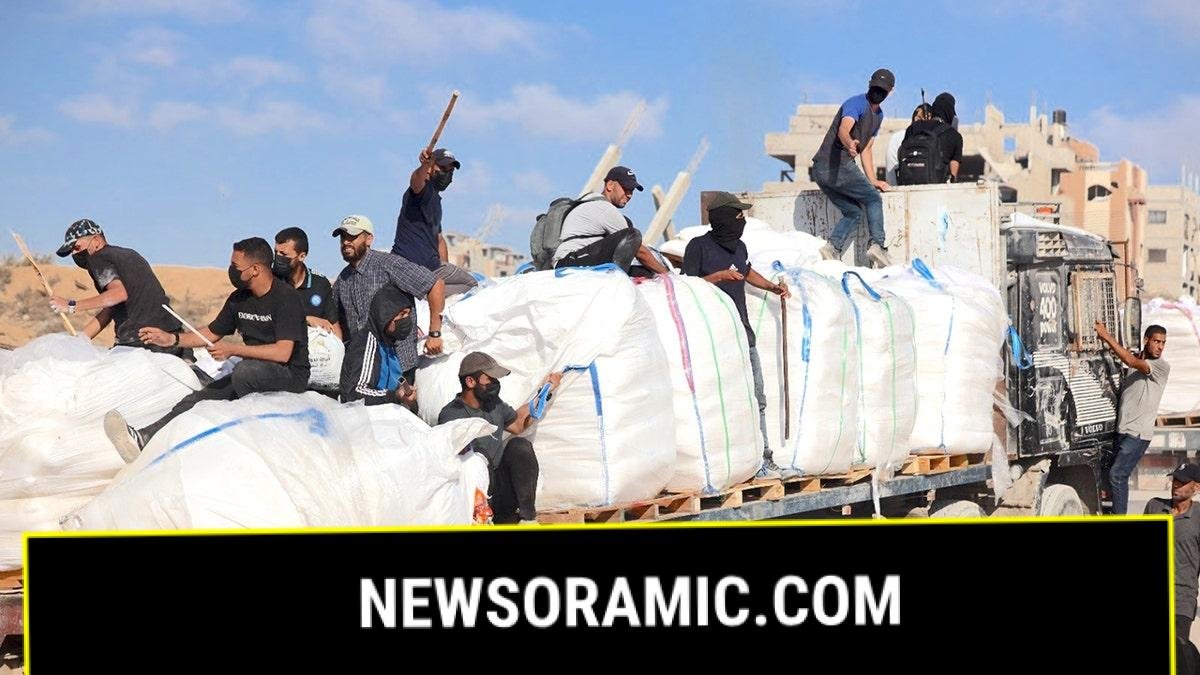 Hamas terrorists carrying clubs and firearms secure, and divert humanitarian aid trucks in the northern Gaza area of Jabaliya on June. 25