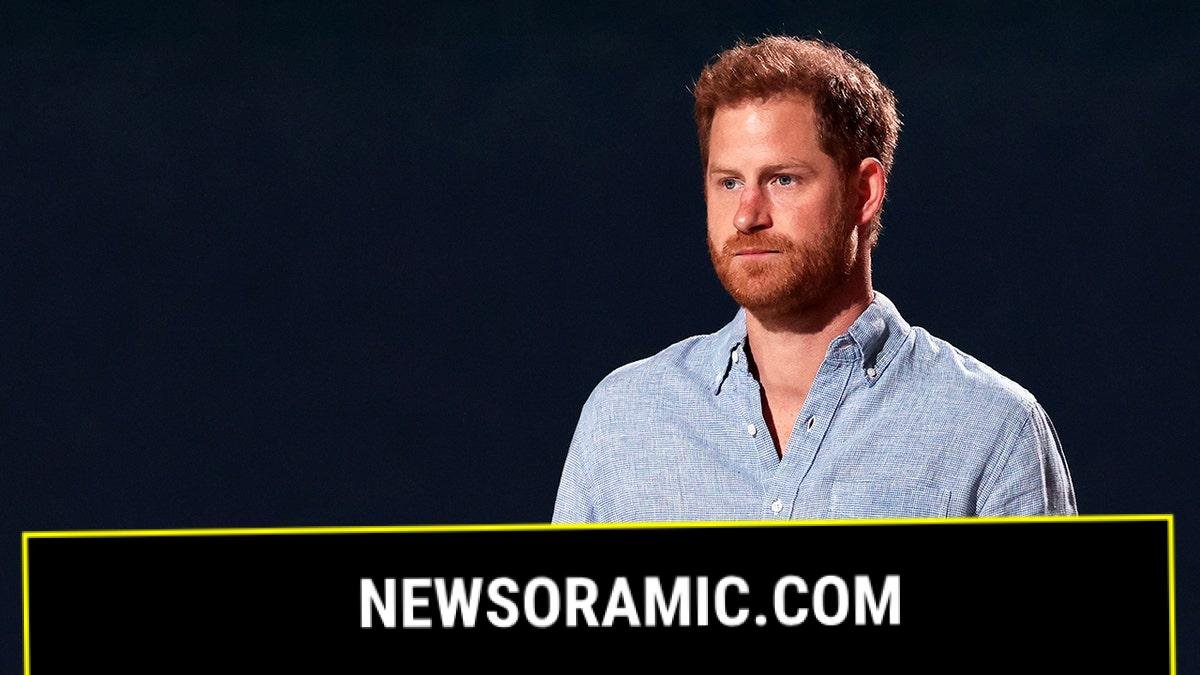Prince Harry wearing a light blue shirt looking serious.