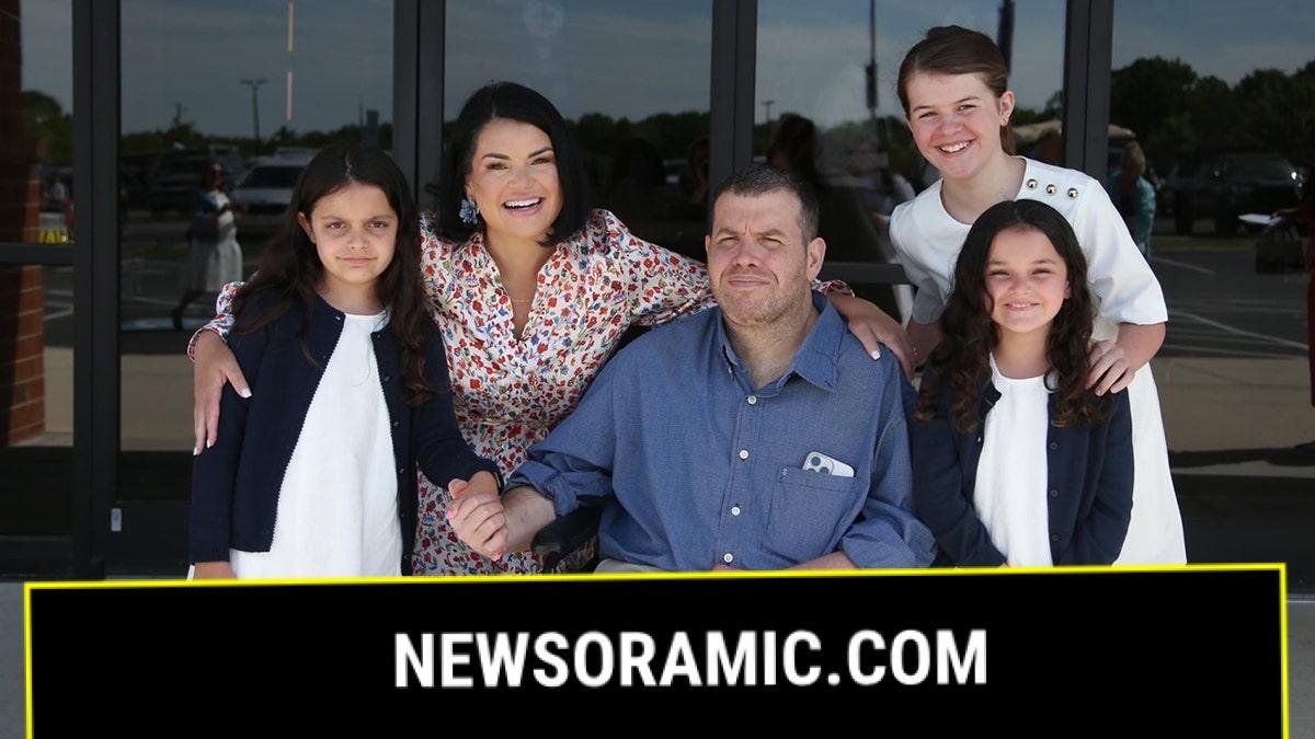 Michael Verardo with wife Sarah and their three daughters outside a building smiling together.