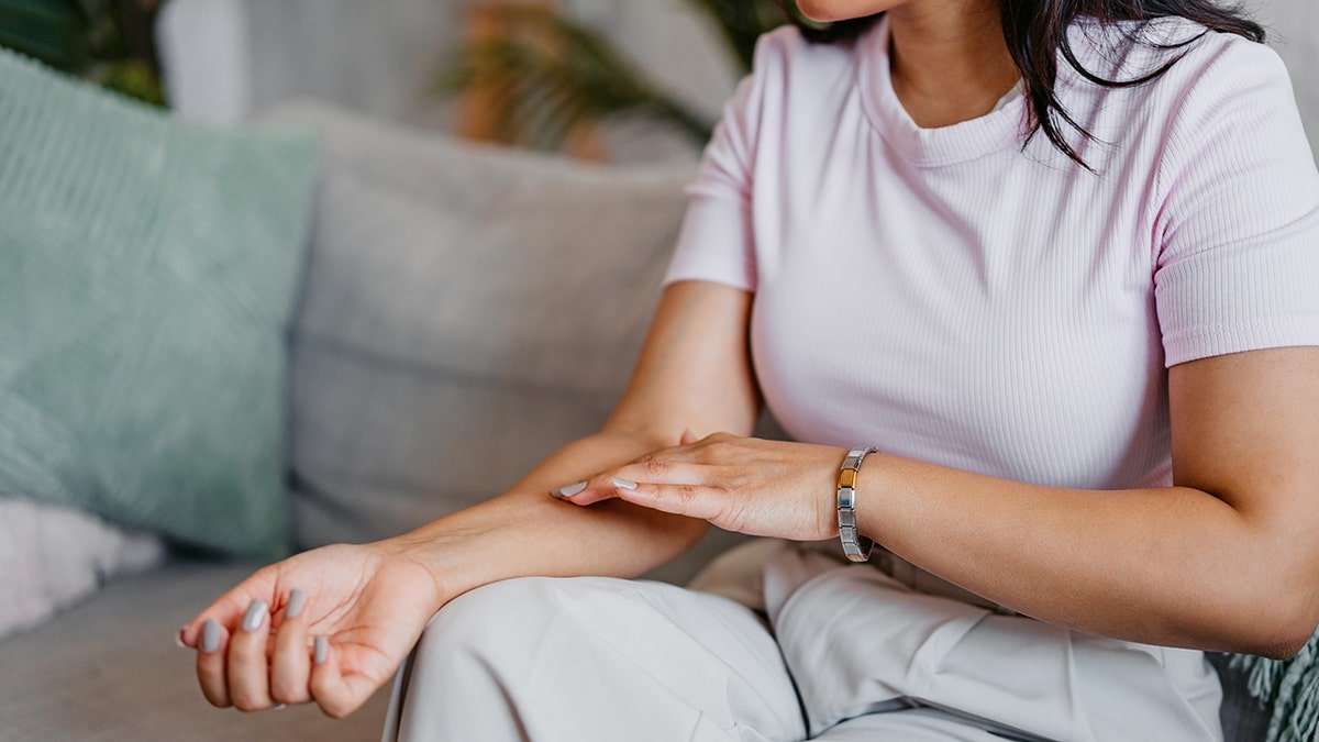 woman examines skin on arm