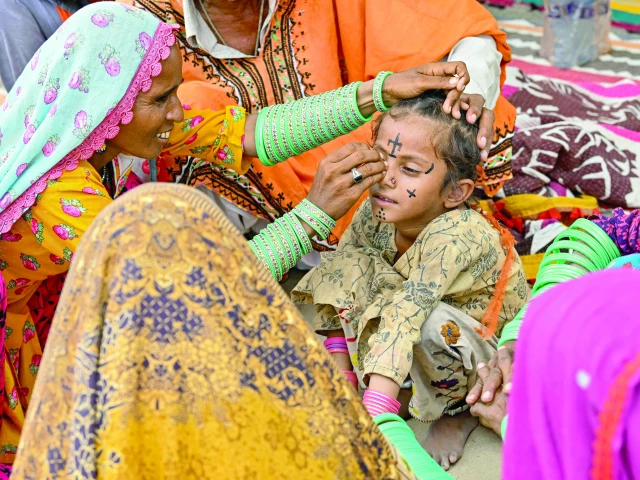 tattoo artist guddi manthar draws an indigenous tattoo on seven year old champa s face at the jogi colony in umerkot photo afp