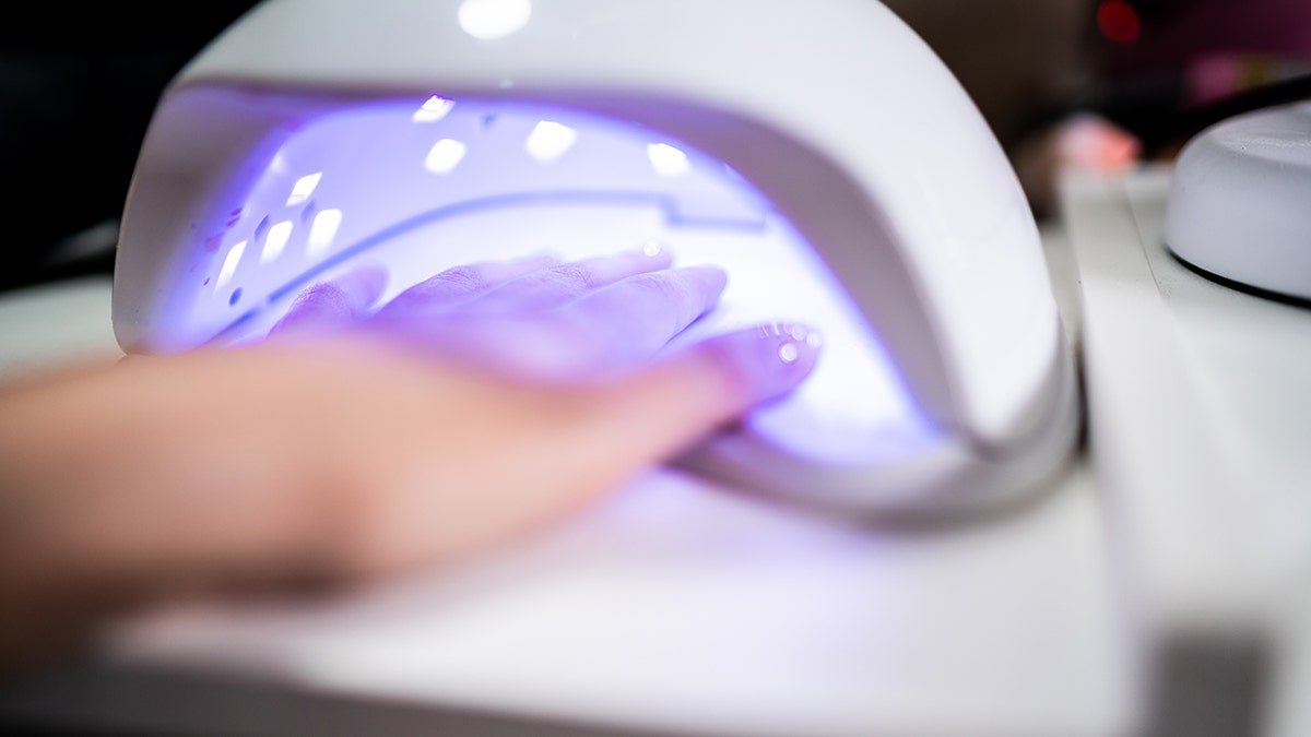 Woman's hand inside UV lamp for nails at a beauty salon