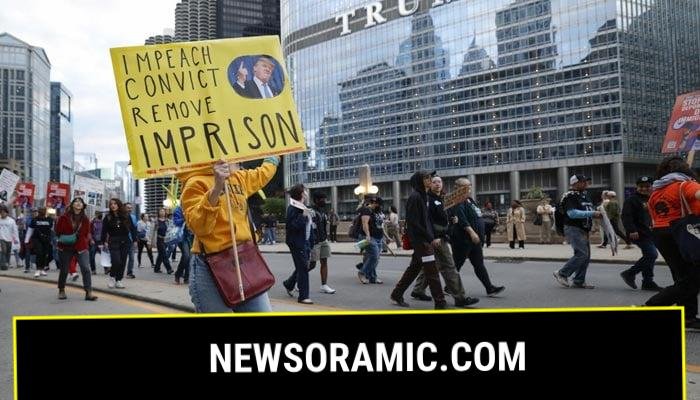 People hold anti-Trump signs as they march past Trump International Hotel & Tower in Chicago during a demonstration against the planned deployment of National Guard troops on September 6, 2025. — AFP