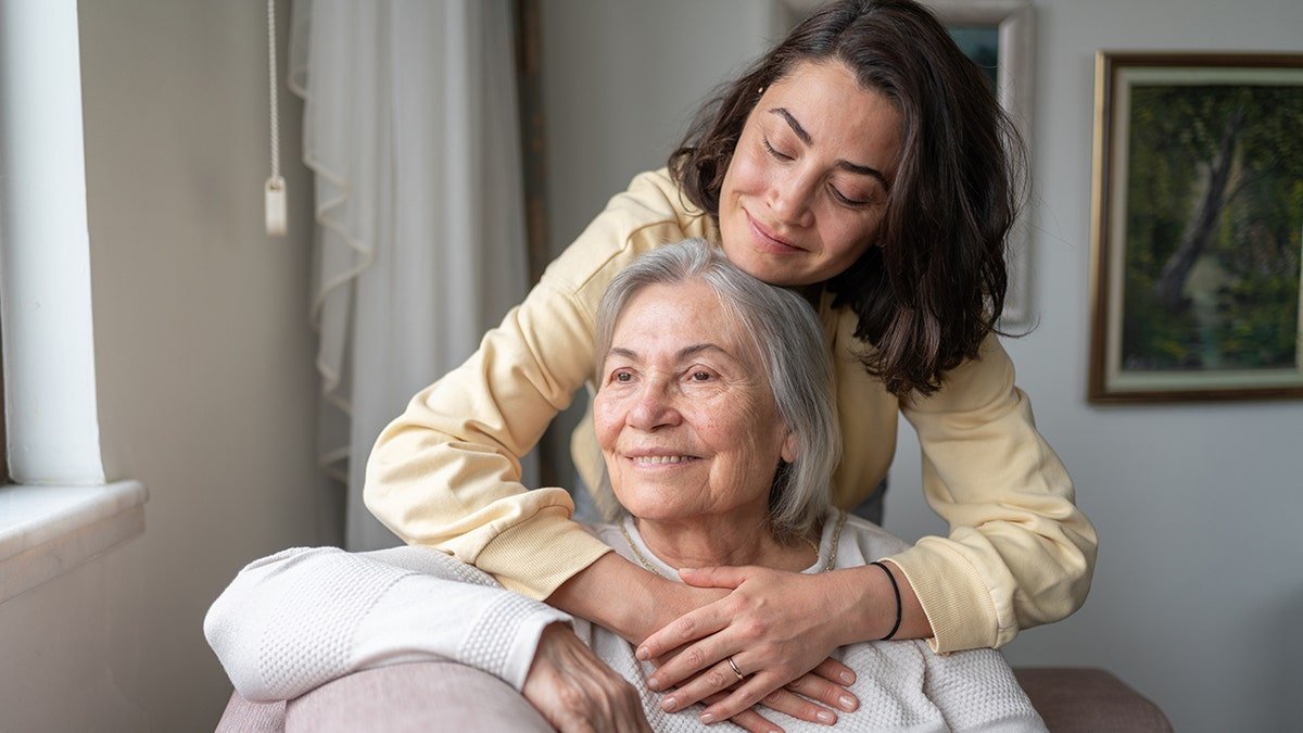 Woman hugging older woman, may have Parkinson's disease