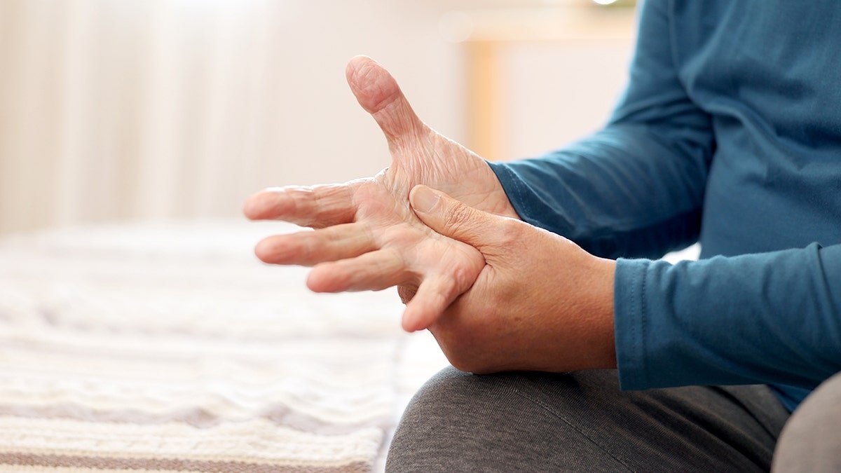 Senior man holding hands due to Parkinson's