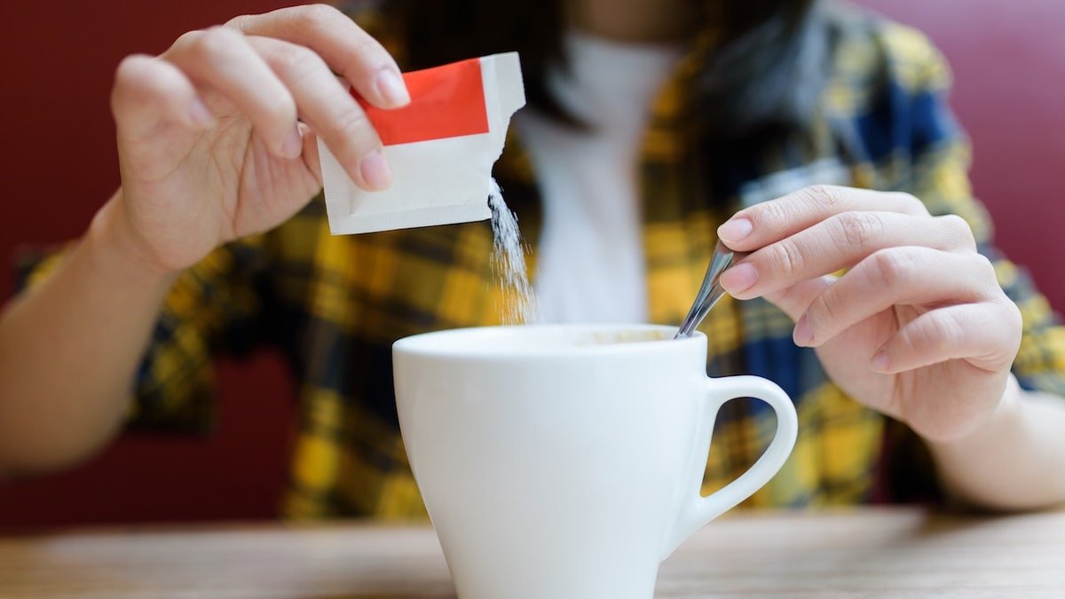Woman pouring sugar into mug