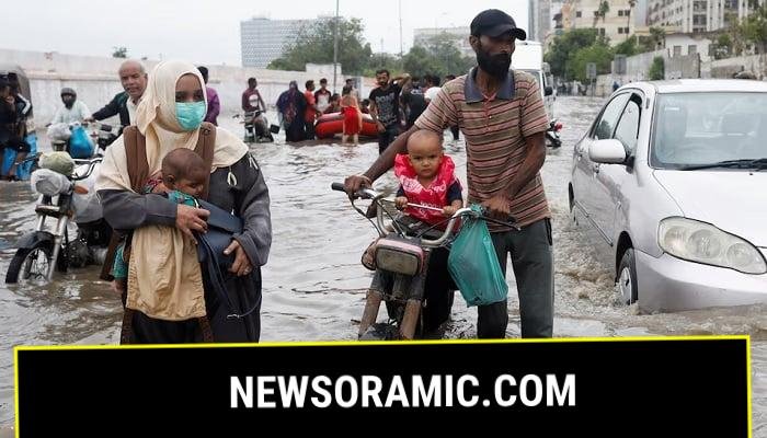 A family wades through a flooded road during the monsoon season in Karachi. —Reuters/File