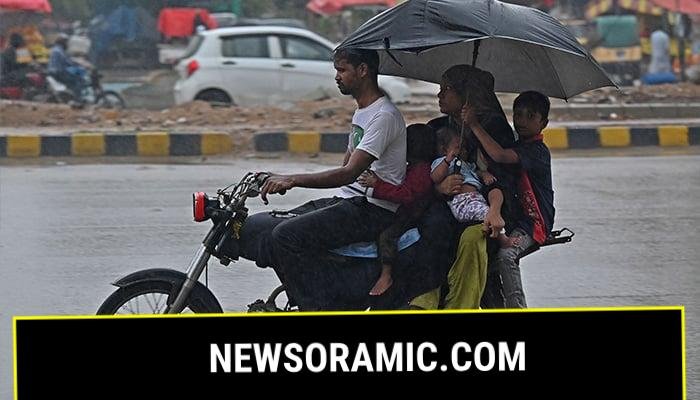A family rides a motorcycle along a street during rainfall in Karachi on September 9, 2025. — AFP