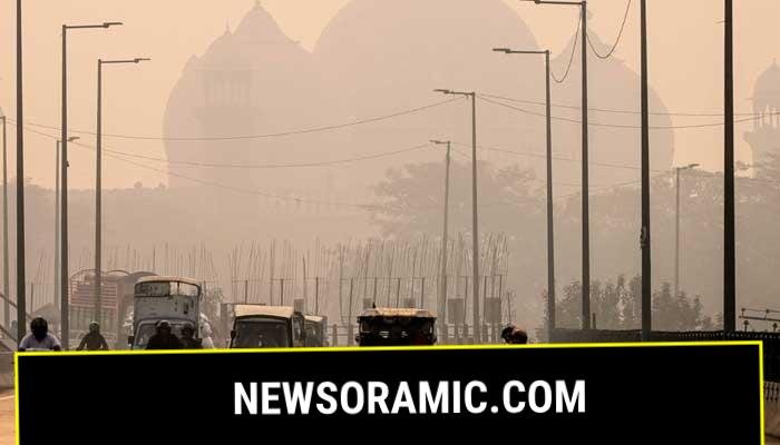 Commuters ride along a street engulfed in smog, in Lahore on November 5, 2024. — AFP