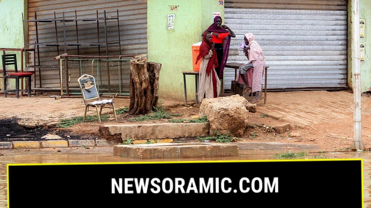 Women gather along the side of a flooded street