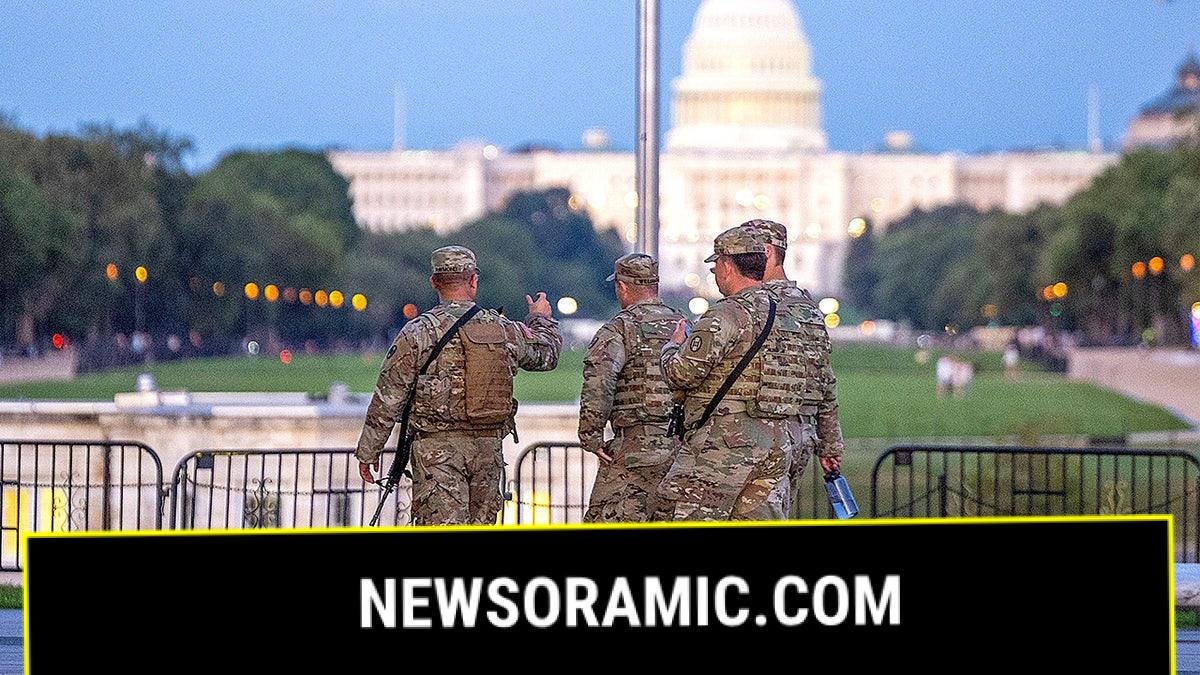 Armed National Guard troops patrol with the U.S. Capitol in the background amid an increased security presence in Washington.