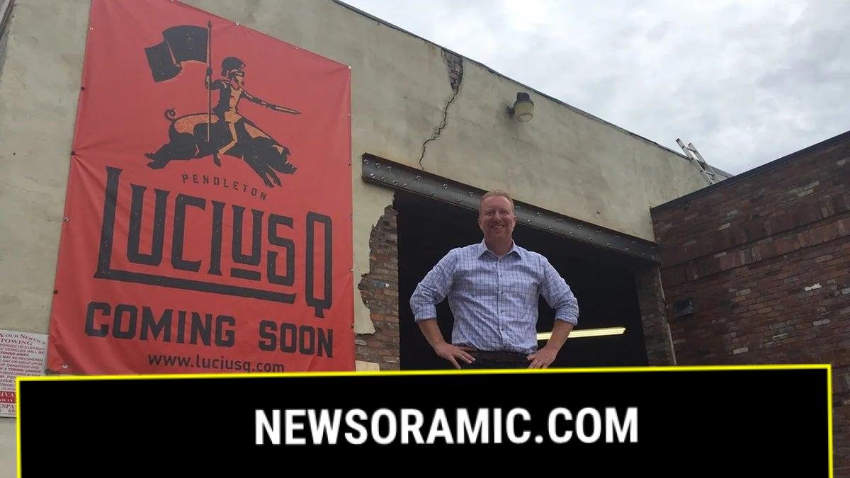 Lucius Q co-owner Aaron Sharpe standing outside building with "coming soon" sign for restaurant in 2017