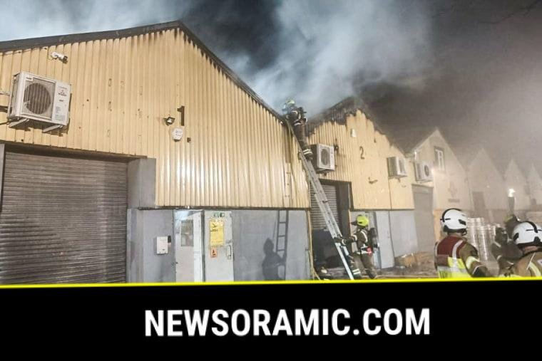 Smoke billows from The Cromwell Industrial Estate building as firefighters surround it